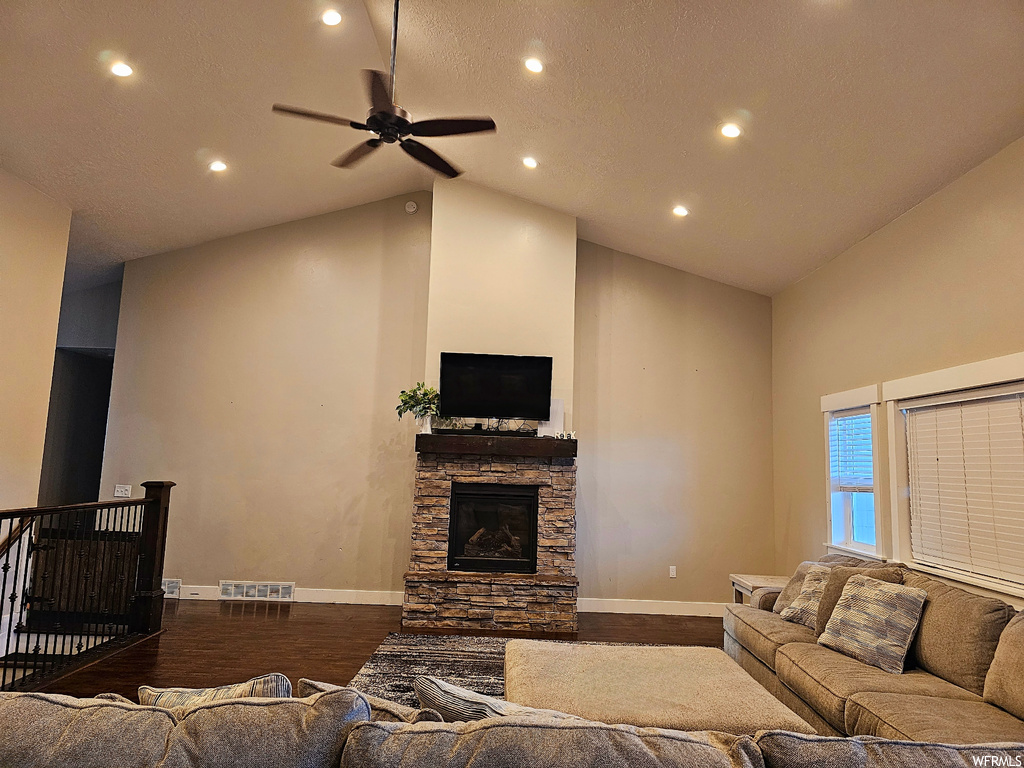 Hardwood floored living room featuring a textured ceiling, lofted ceiling, a fireplace, a high ceiling, and ceiling fan