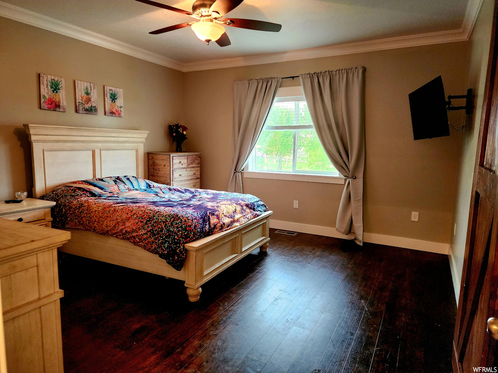 Bedroom with dark hardwood floors, ornamental molding, and ceiling fan
