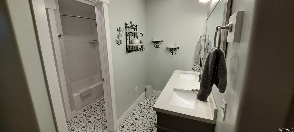Bathroom with tile flooring, tiled shower / bath combo, and double sink vanity
