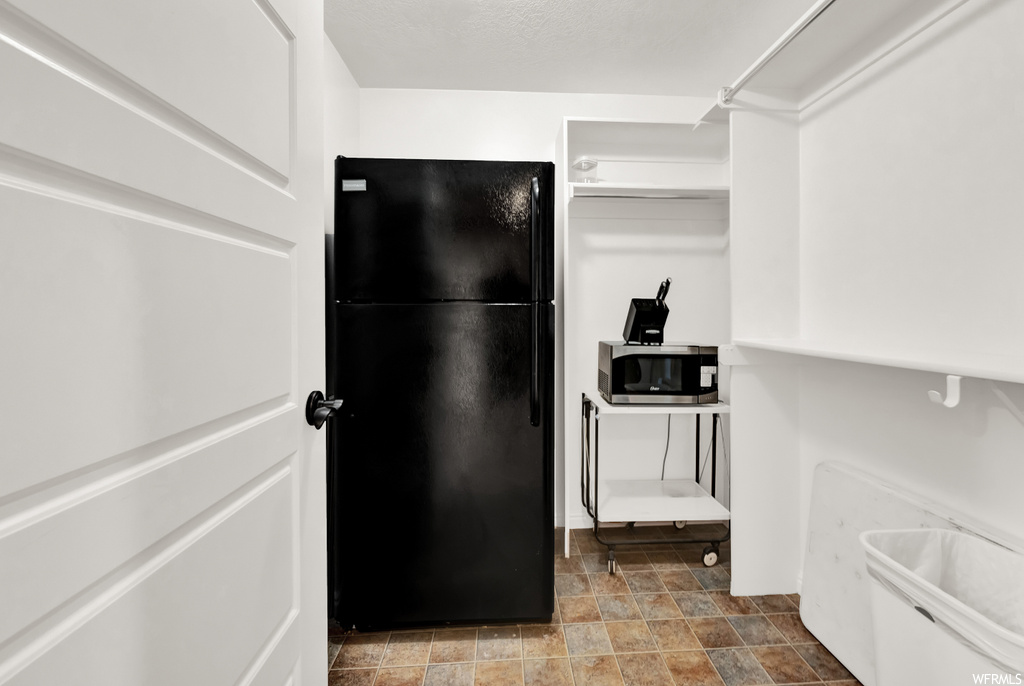 Interior space with black fridge and dark tile flooring