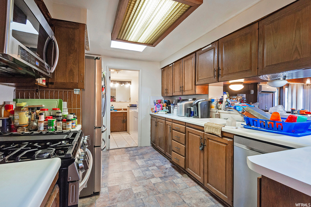 Kitchen featuring countertops light, appliances with stainless steel finishes, light tile floors, and washbasin