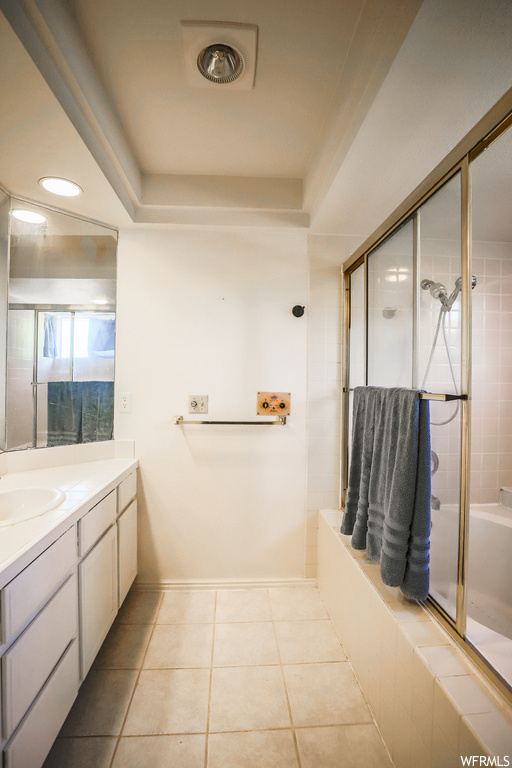 Bathroom with a tray ceiling, vanity, and light tile flooring