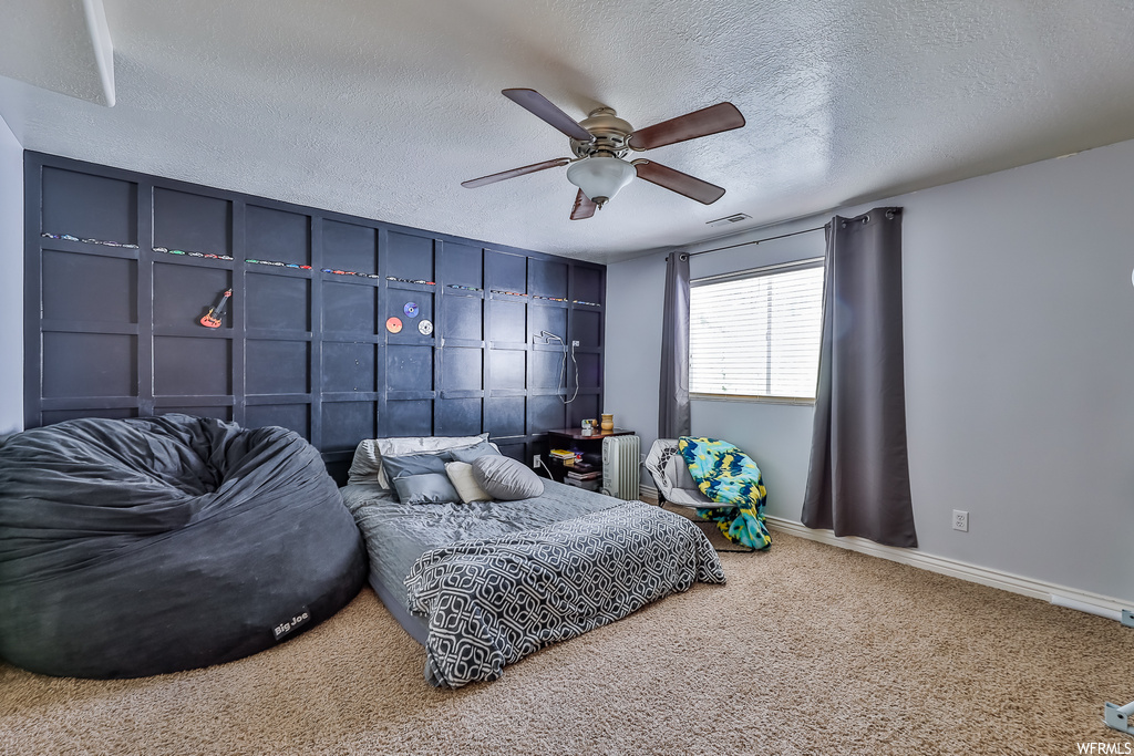 Carpeted bedroom with ceiling fan and a textured ceiling