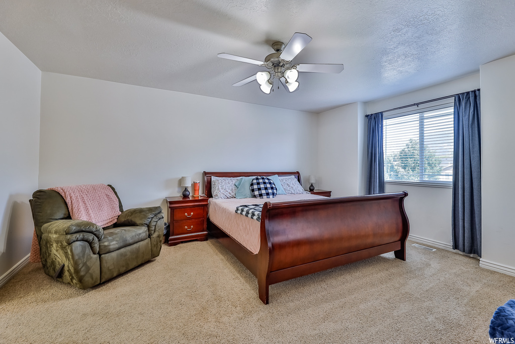 Carpeted bedroom featuring a textured ceiling and ceiling fan
