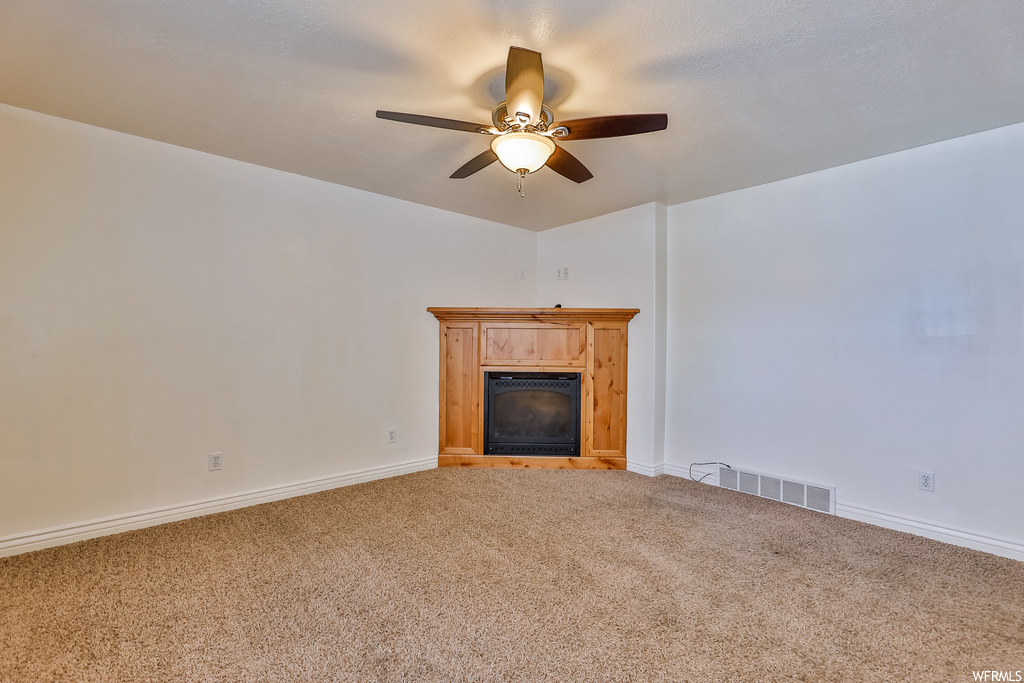 Living room featuring light carpet, a fireplace, and ceiling fan