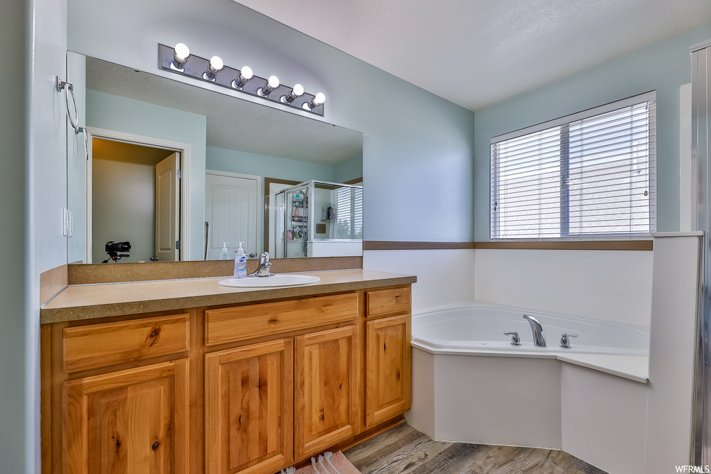 Bathroom with hardwood floors, vanity, mirror, and independent shower and bath