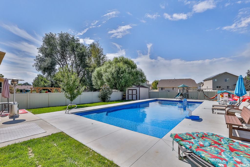 View of pool with a patio area and a storage shed
