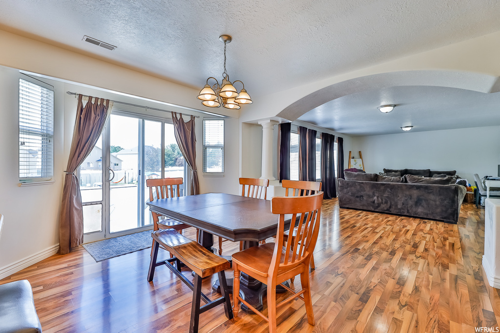 Dining area with light hardwood floors, a healthy amount of sunlight, and a textured ceiling