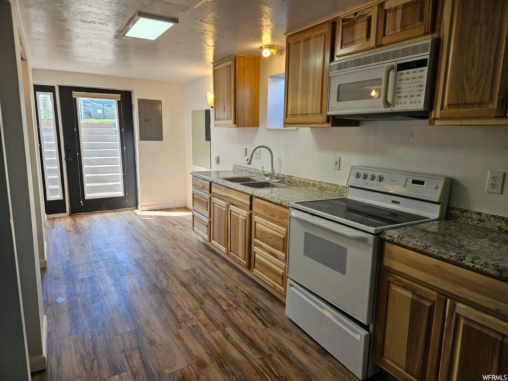Kitchen with white appliances, wood-type flooring, and brown cabinets