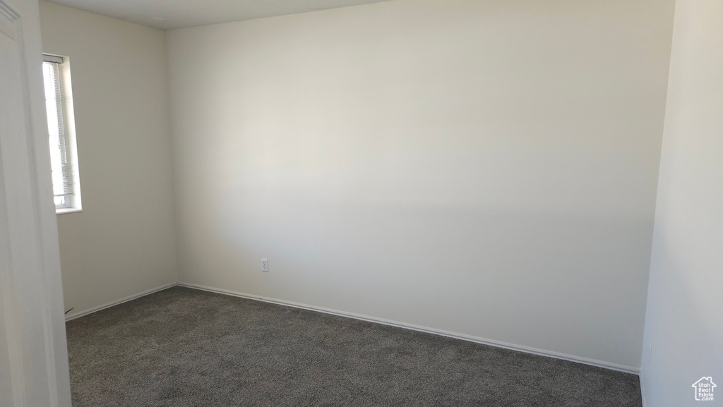 Empty room with dark carpet and plenty of natural light