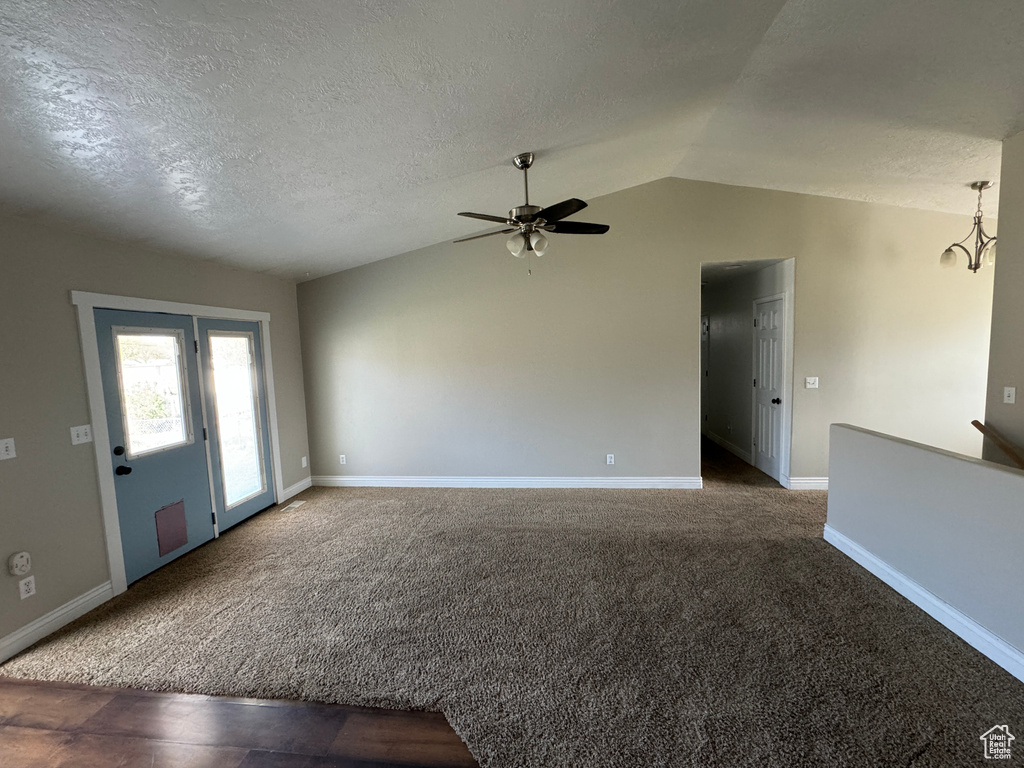 Foyer featuring lofted ceiling, ceiling fan, carpet, and a textured ceiling