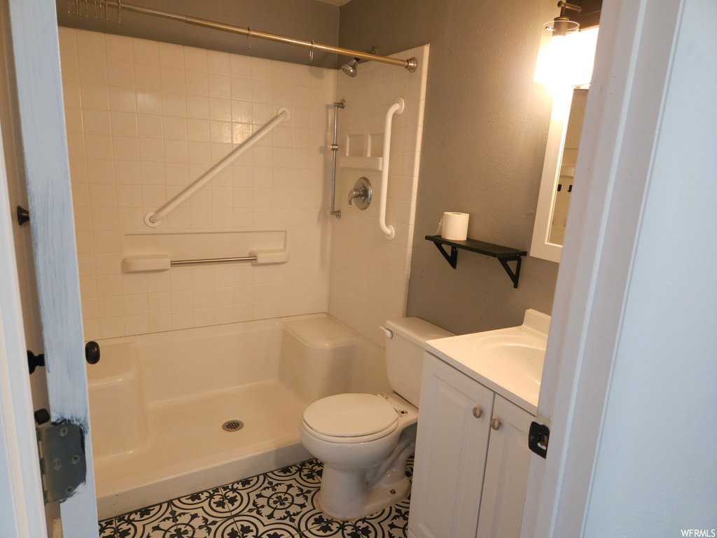 Bathroom featuring tile flooring, mirror, a tile shower, and vanity