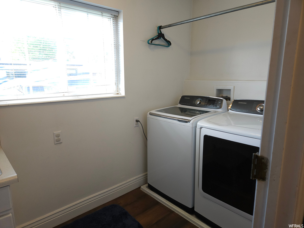 Washroom with a wealth of natural light, dark hardwood flooring, and washer and dryer