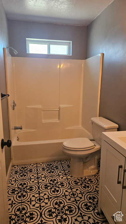 Full bathroom featuring tile flooring, a textured ceiling, toilet, vanity, and shower / bathtub combination