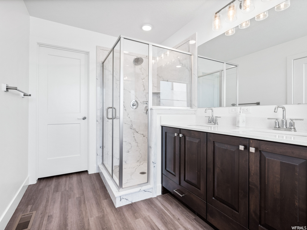 Bathroom with an enclosed shower, hardwood flooring, mirror, and dual large bowl vanity