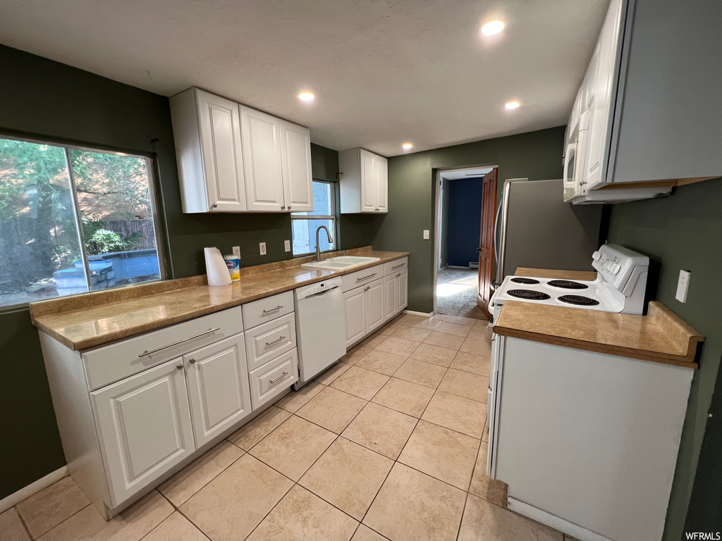 Kitchen with light countertops, white cabinets, white appliances, and light tile floors