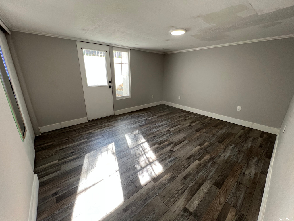Empty room featuring dark hardwood floors and ornamental molding