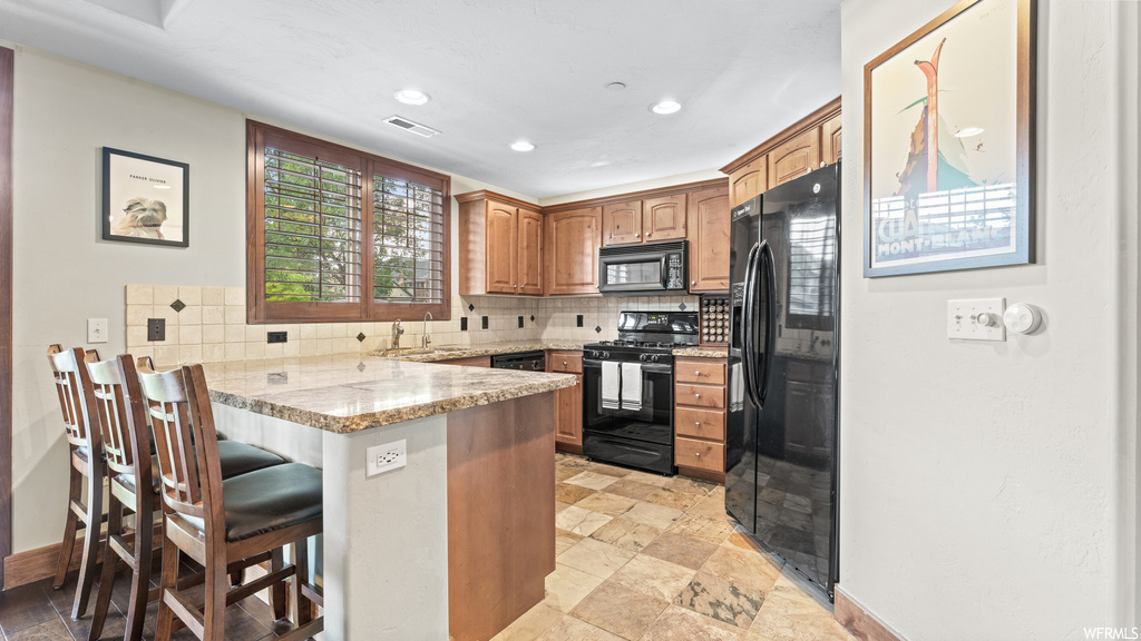 Kitchen featuring light countertops, black appliances, backsplash, and light tile floors