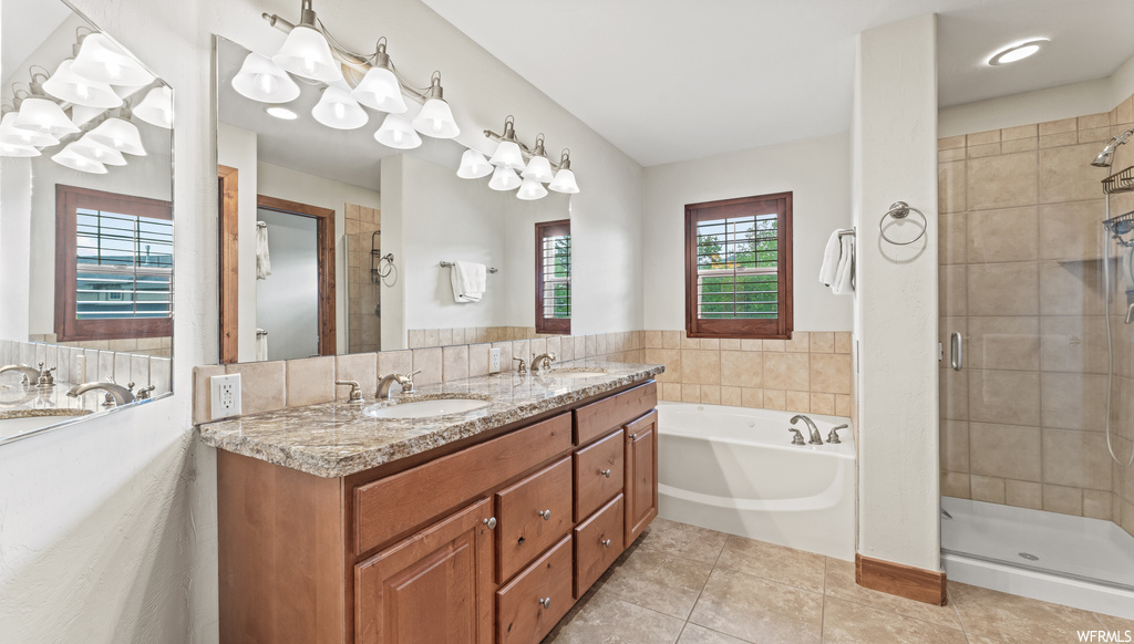 Bathroom featuring independent shower and bath, dual vanity, mirror, and light tile flooring