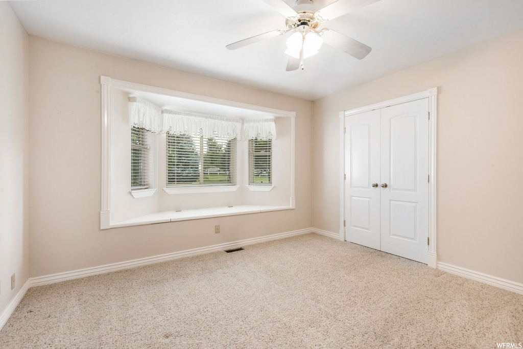 Carpeted spare room with ceiling fan