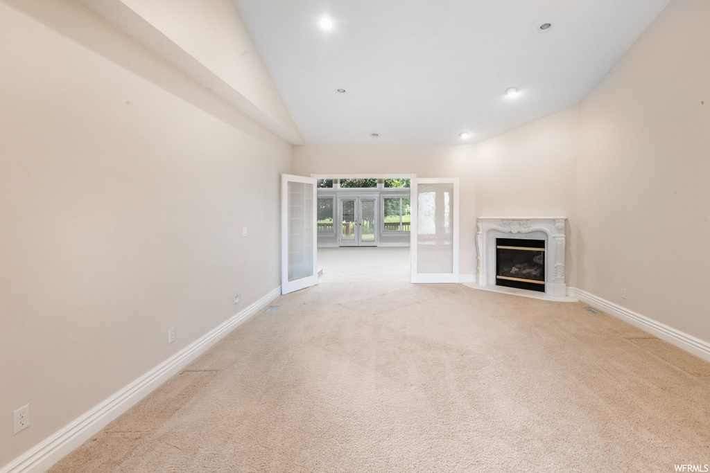Living room featuring a fireplace, light carpet, and vaulted ceiling