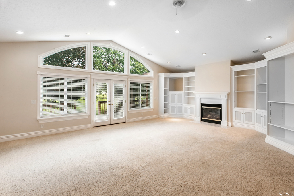 Living room featuring a fireplace, vaulted ceiling, a high ceiling, and light carpet