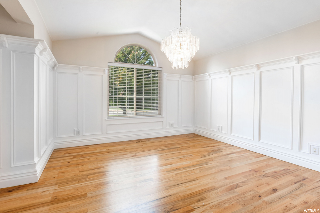 Unfurnished room featuring light hardwood flooring and vaulted ceiling