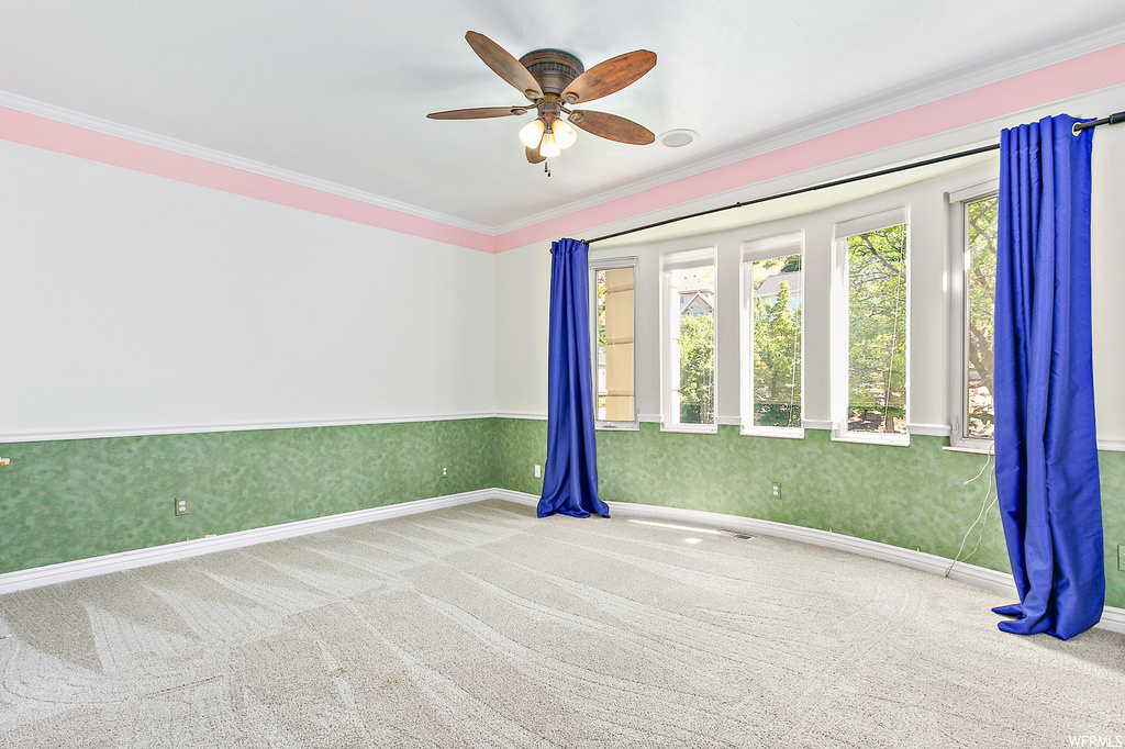Empty room featuring ornamental molding, light carpet, and ceiling fan