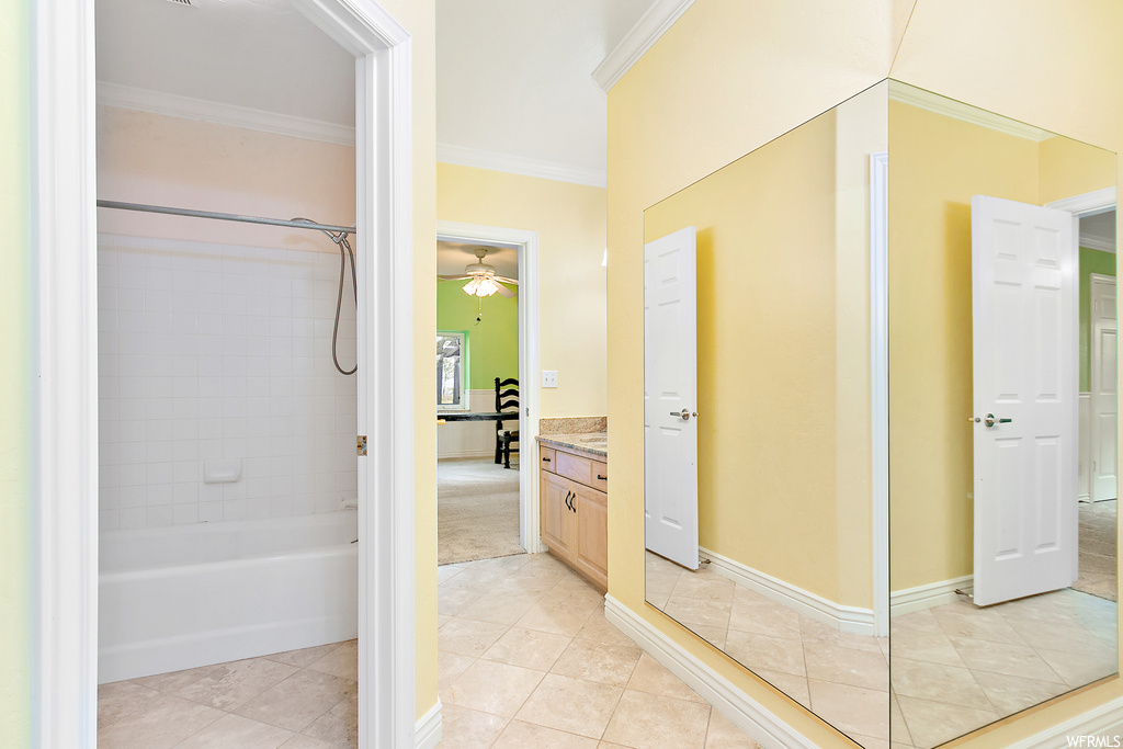 Bathroom featuring ornamental molding, shower / tub combination, ceiling fan, vanity, and light tile flooring