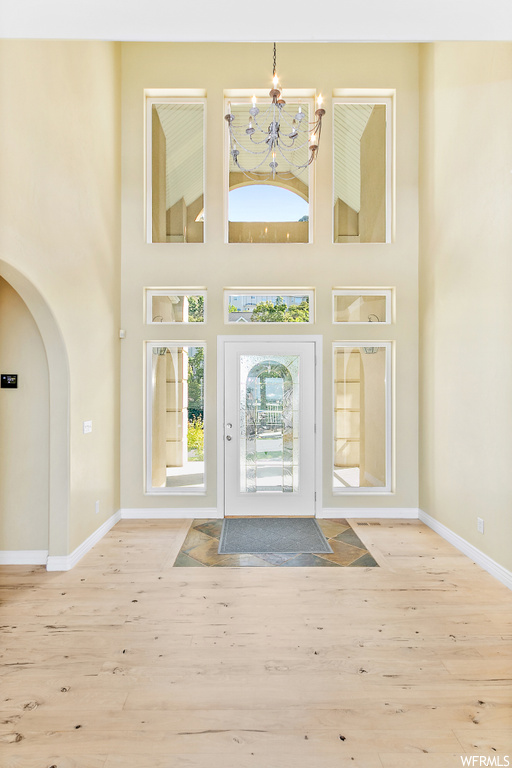 Wood floored foyer entrance with a chandelier and a high ceiling