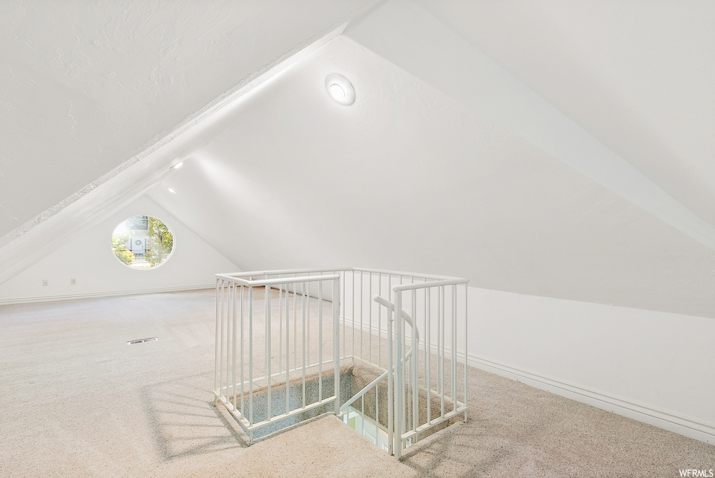 Bonus room with light carpet and vaulted ceiling