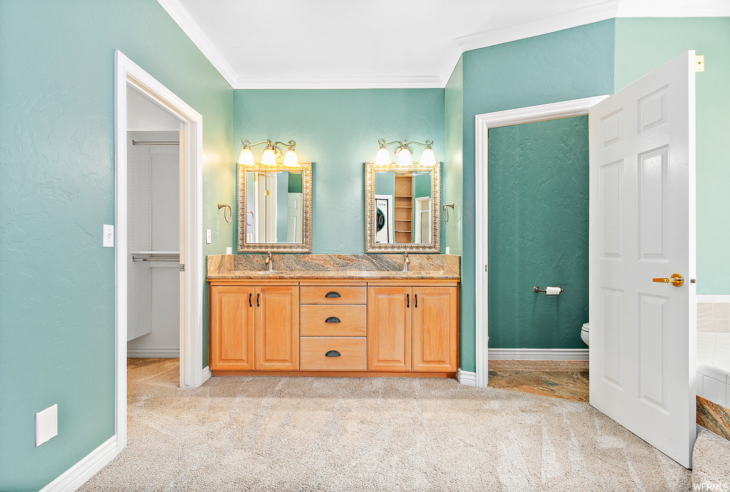 Bathroom with dual vanity, ornamental molding, and mirror
