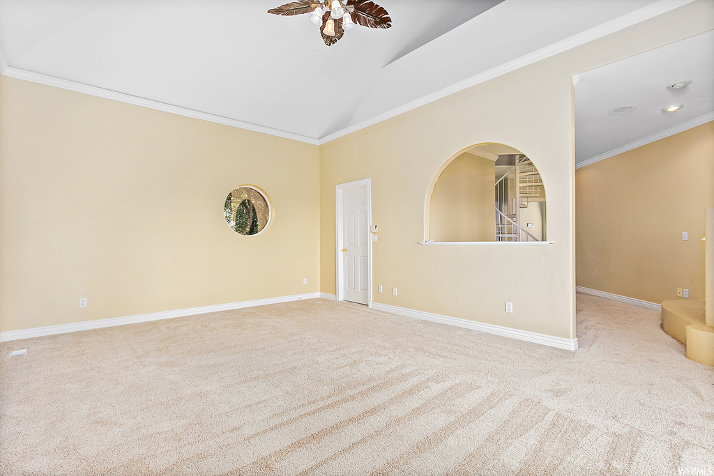 Spare room featuring ornamental molding, light carpet, and lofted ceiling