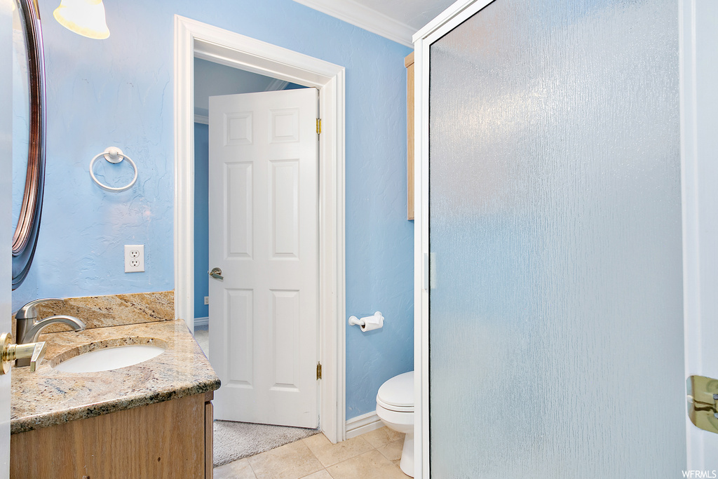 Bathroom with vanity, ornamental molding, mirror, and light tile floors