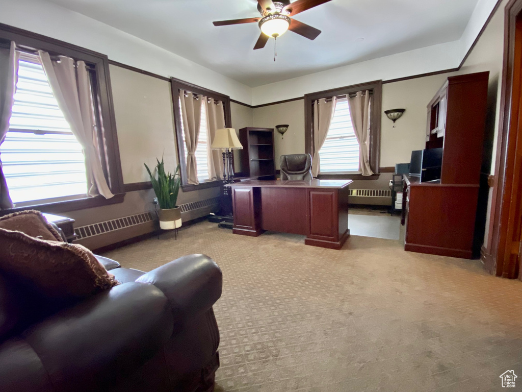 Carpeted living room with a healthy amount of sunlight, ceiling fan, and radiator