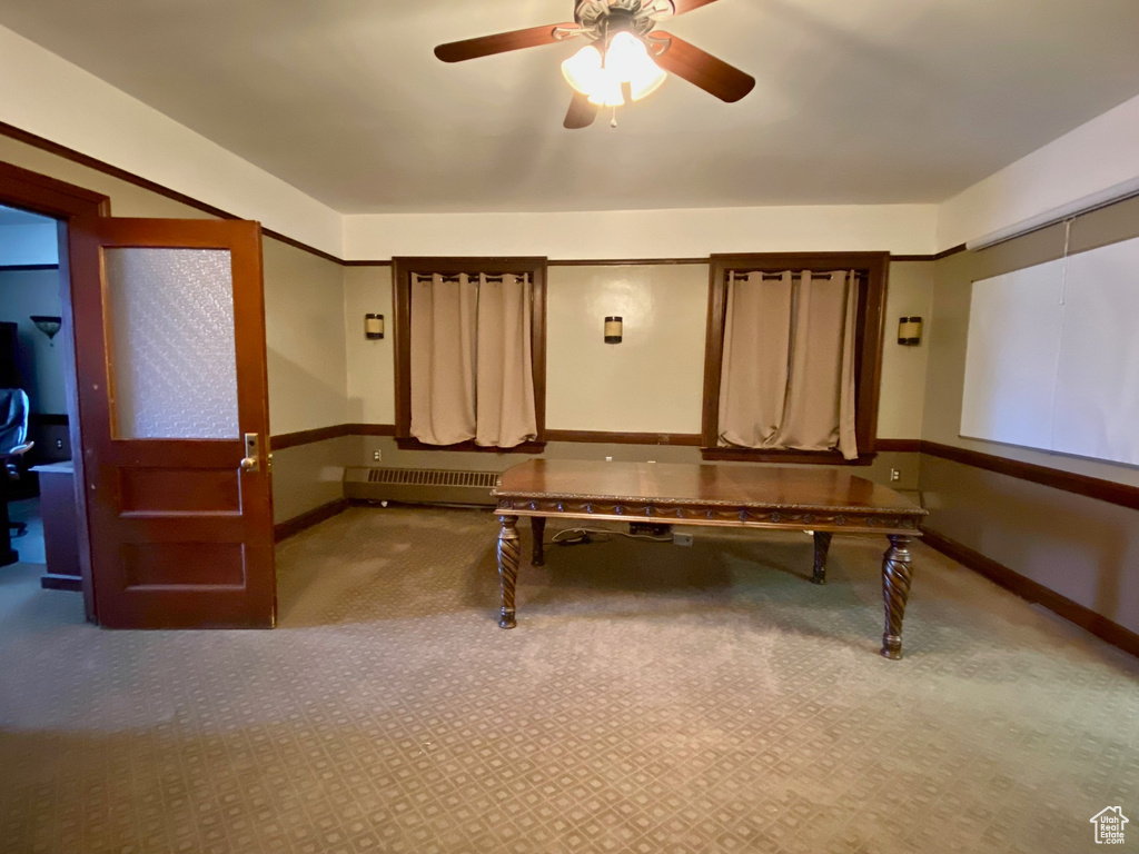 Rec room with carpet flooring, ceiling fan, and radiator heating unit