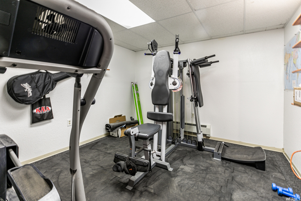 Workout room with a drop ceiling and a baseboard radiator