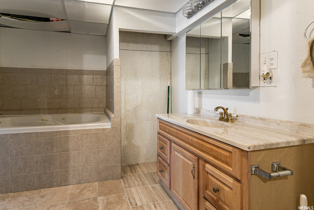 Bathroom with vanity, mirror, tiled bath, and light tile floors