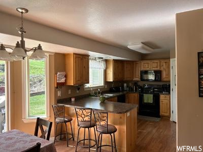 Kitchen with a kitchen island, dark countertops, range, brown cabinets, wood-type flooring, hanging light fixtures, and backsplash