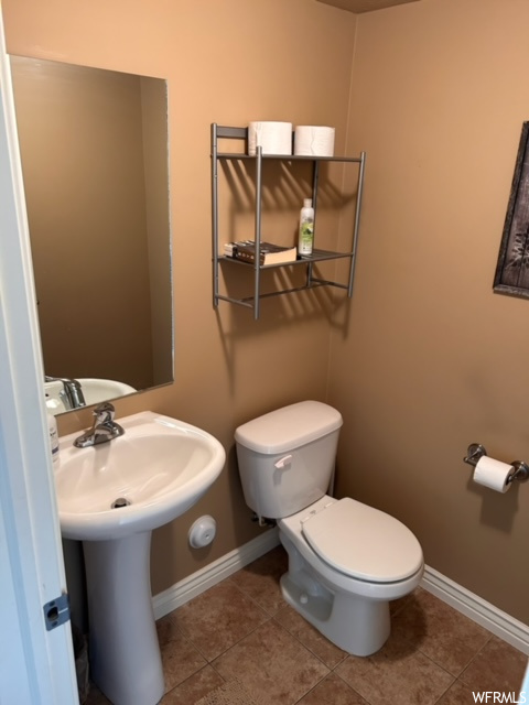 Bathroom featuring dark tile flooring, mirror, and washbasin