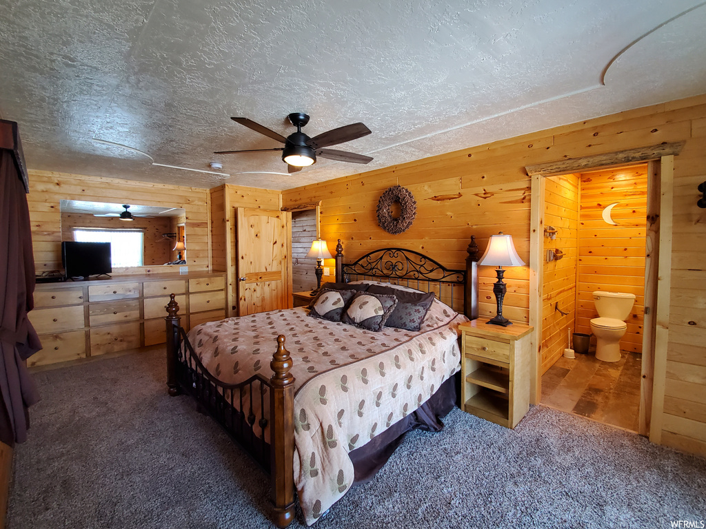 Bedroom with ceiling fan, wood walls, a textured ceiling, and carpet flooring