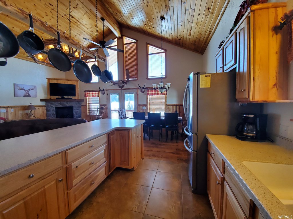 Kitchen with brown cabinets, light countertops, ceiling fan, lofted ceiling, dark tile floors, and wood ceiling