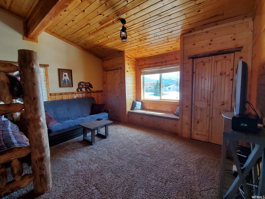 Living room with carpet, wood walls, lofted ceiling with beams, and wooden ceiling