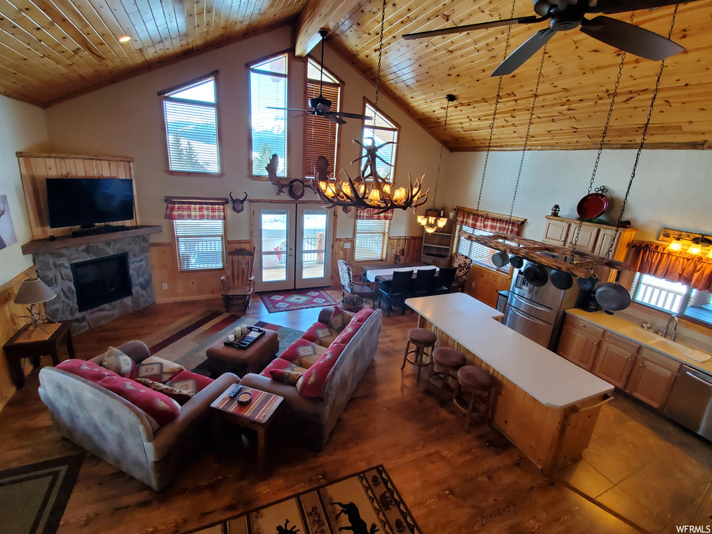 Living room with plenty of natural light, ceiling fan, lofted ceiling, a fireplace, wood ceiling, and a high ceiling