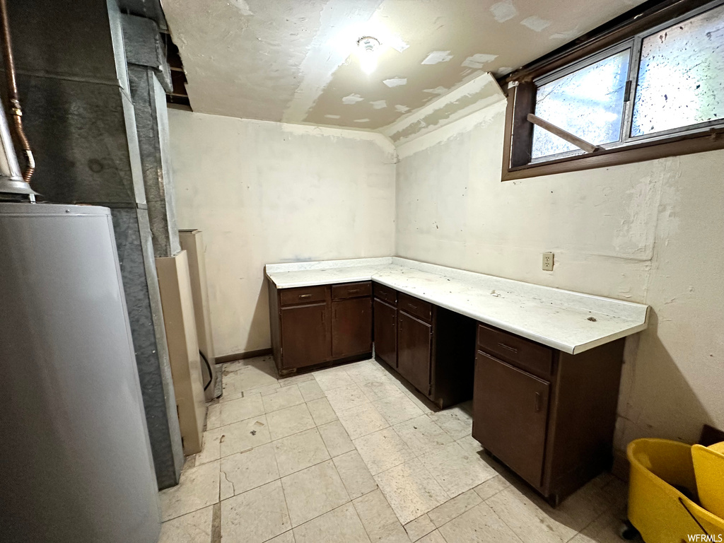 Basement featuring refrigerator and light tile floors