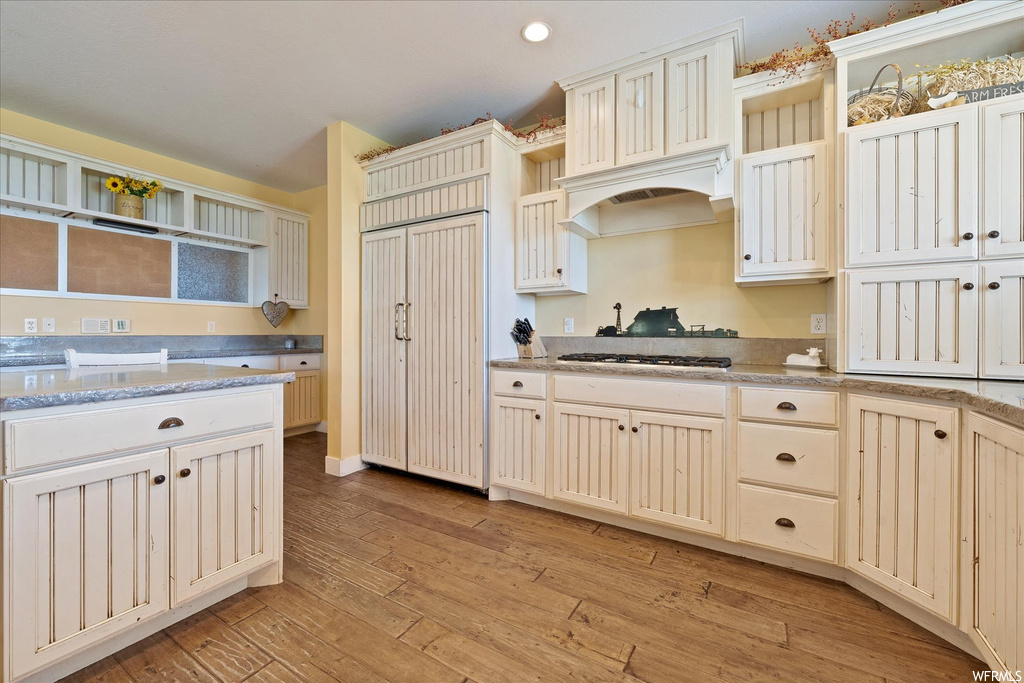 Kitchen featuring premium range hood, light hardwood flooring, and paneled built in refrigerator