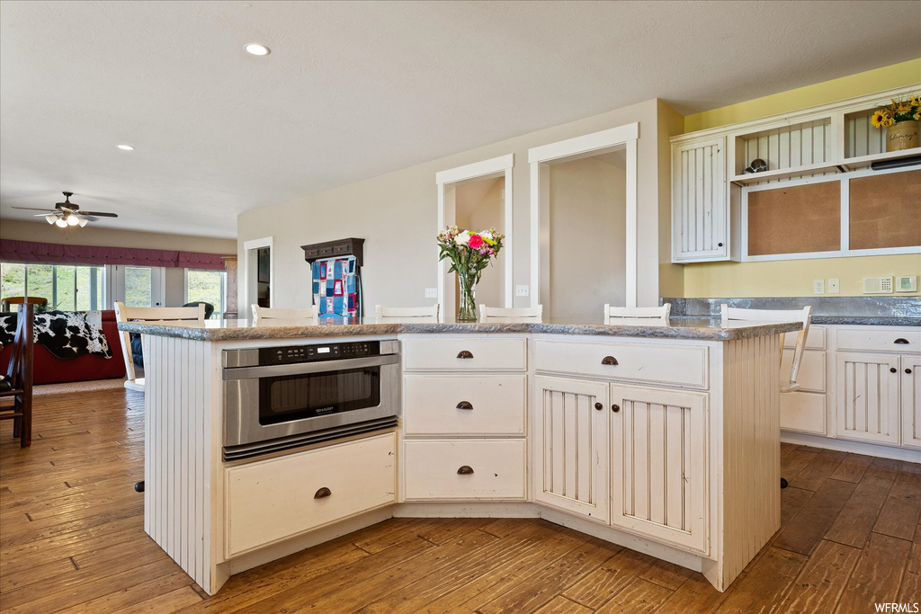 Kitchen featuring light hardwood flooring, stainless steel oven, ceiling fan, and white cabinetry