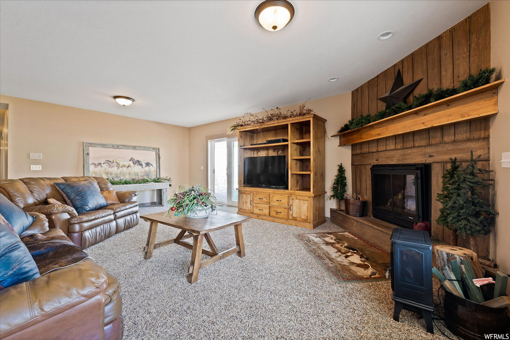 Living room featuring wooden walls, a fireplace, and light carpet