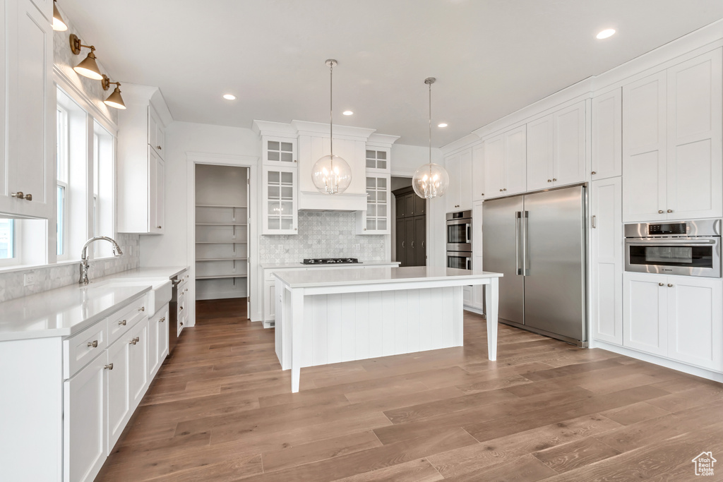 Kitchen with white cabinets, stainless steel appliances, tasteful backsplash, and a center island