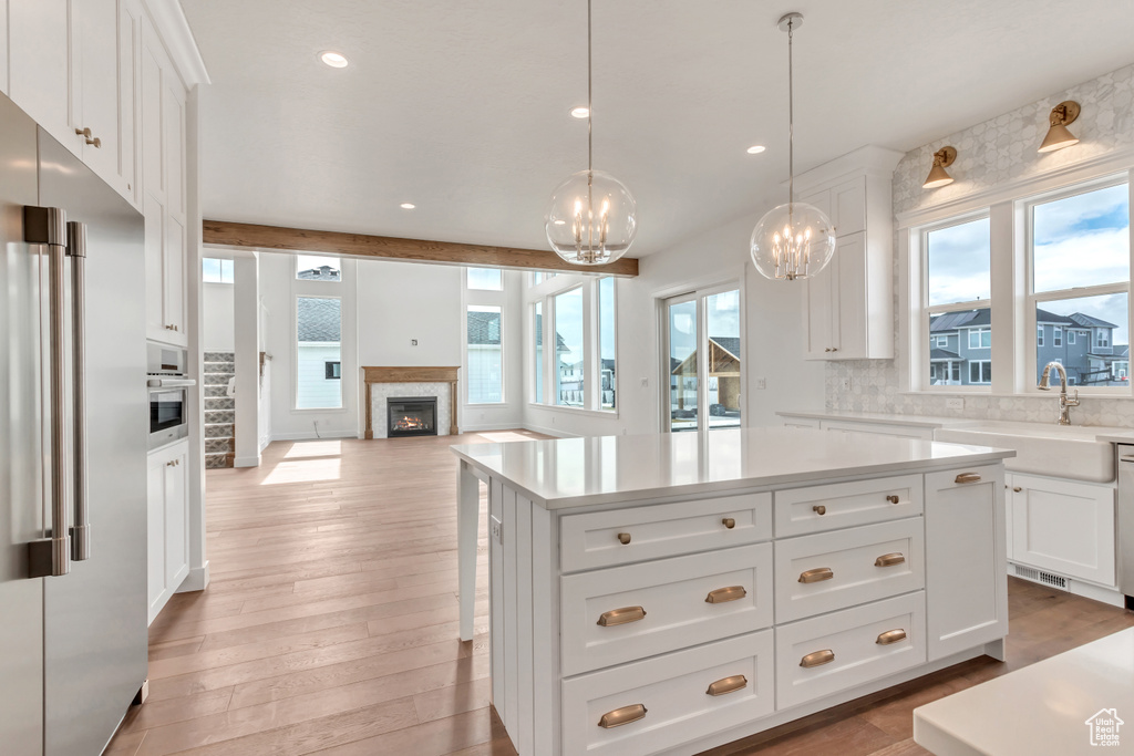 Kitchen with white cabinetry, a kitchen island, light wood-type flooring, and tasteful backsplash